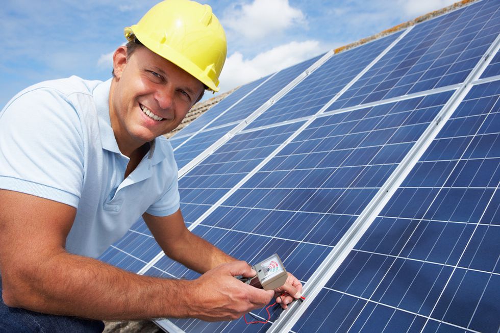 A solar photovoltaic installer installing solar panels on a roof.
