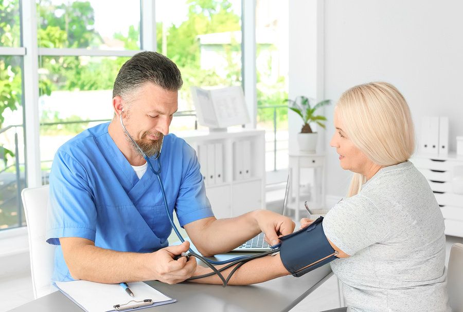 Male physician assistant taking a patient's vitals in a physician's office.