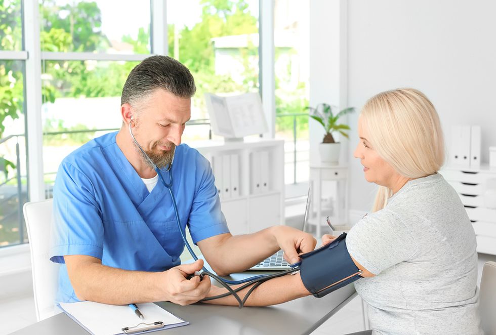 Male physician assistant taking a patient's vitals in a physician's office.