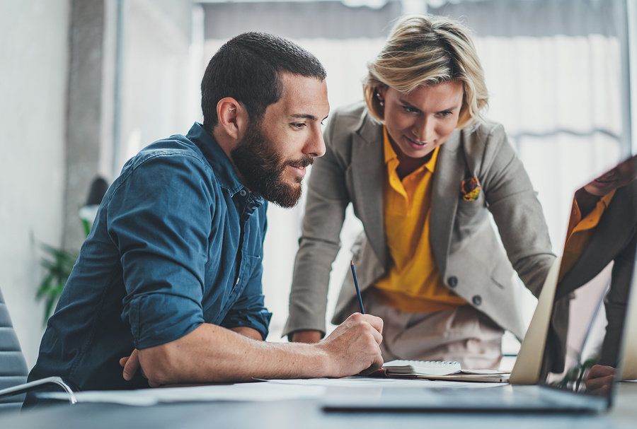 Information security analyst showing a CEO the work he's done on his computer.