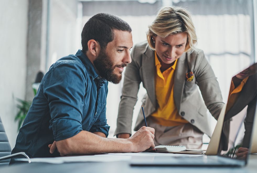 Information security analyst showing a CEO the work he's done on his computer.