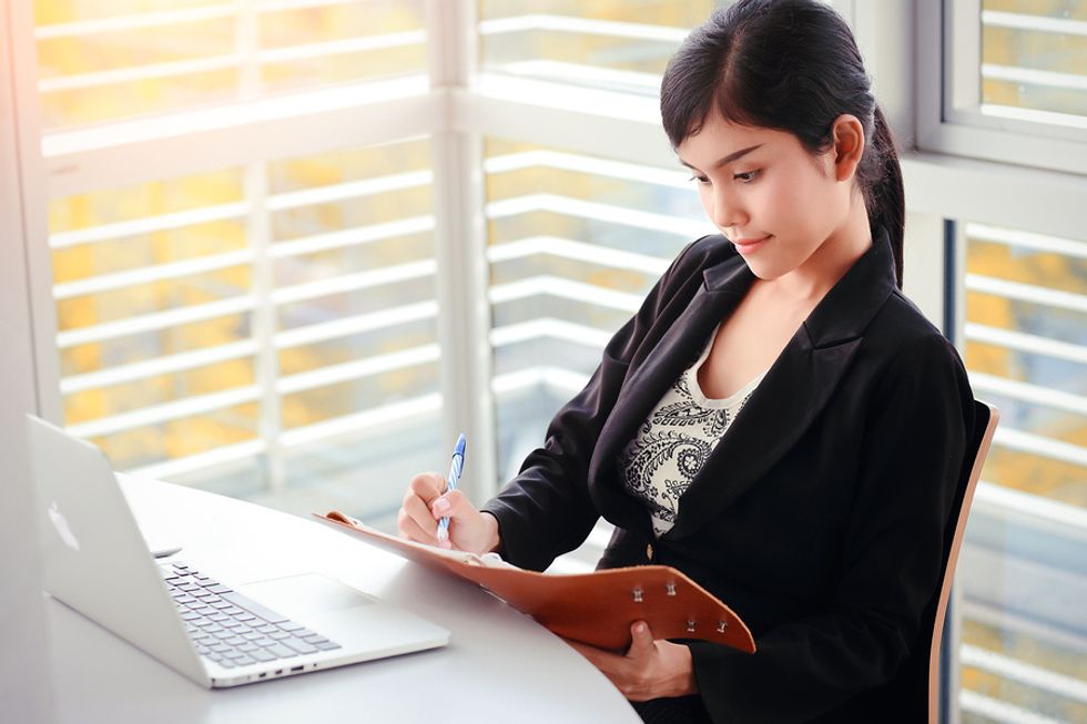 Businesswoman outlining her priorities on a notebook at her desk and making herself more productive at work.