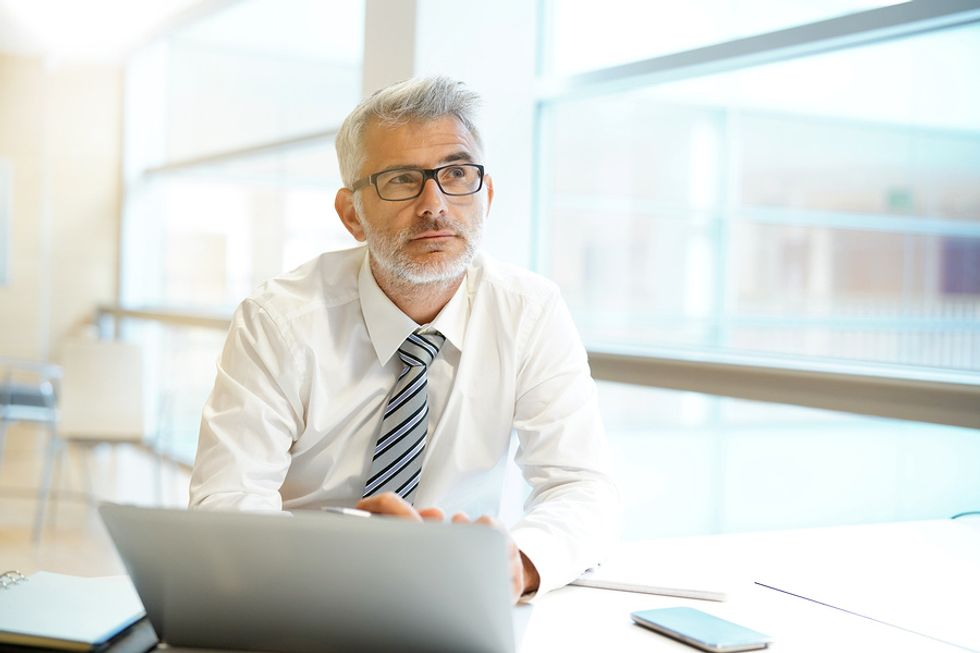 Businessman thinking about what his long-term work goals are in order to be more productive at work.