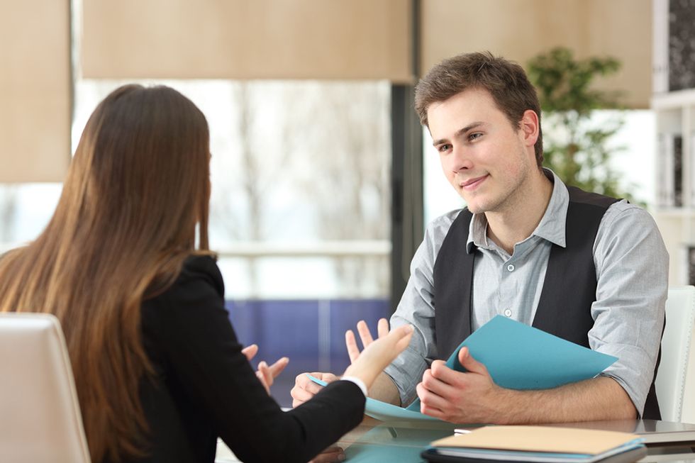 Young businessman listens as his supervisor gives a performance review.