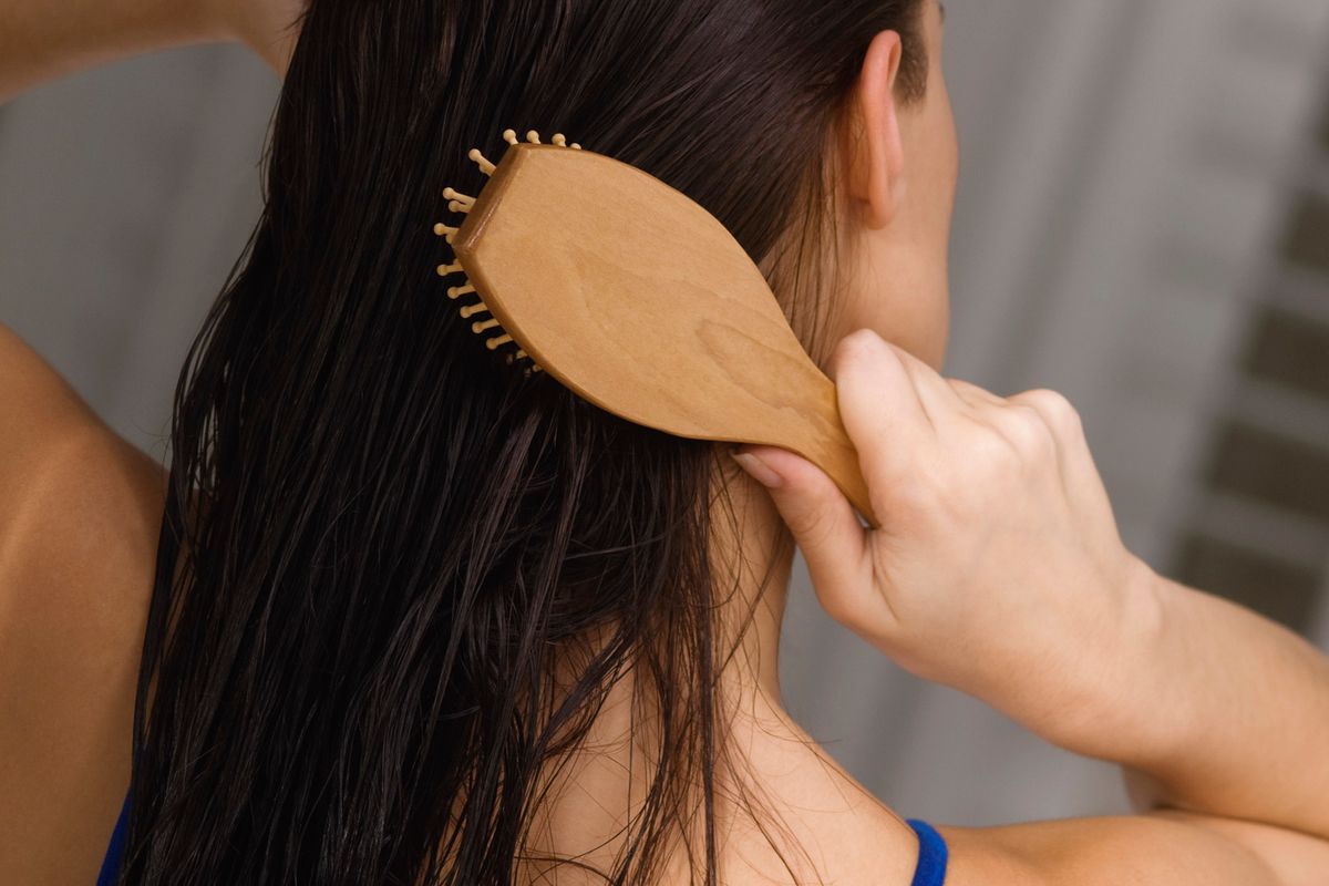 A woman brushes her long brown hair