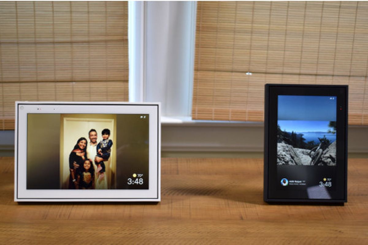 Two framed Portal devices, with screens, seated on a wooden table