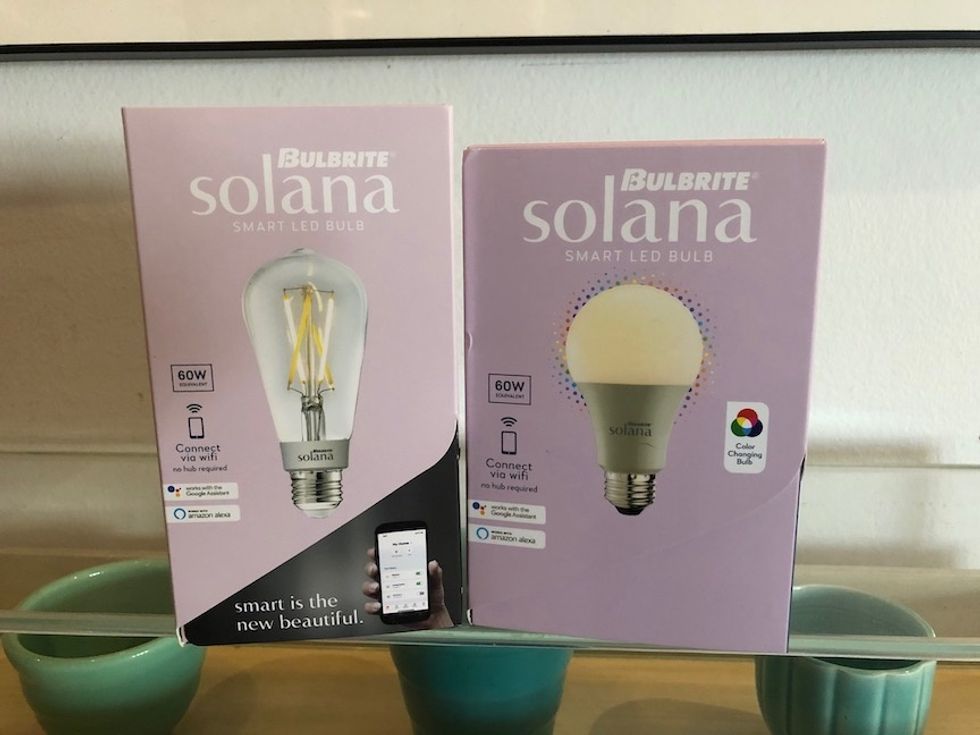 Two boxes of smart light bulbs on top of a glass display