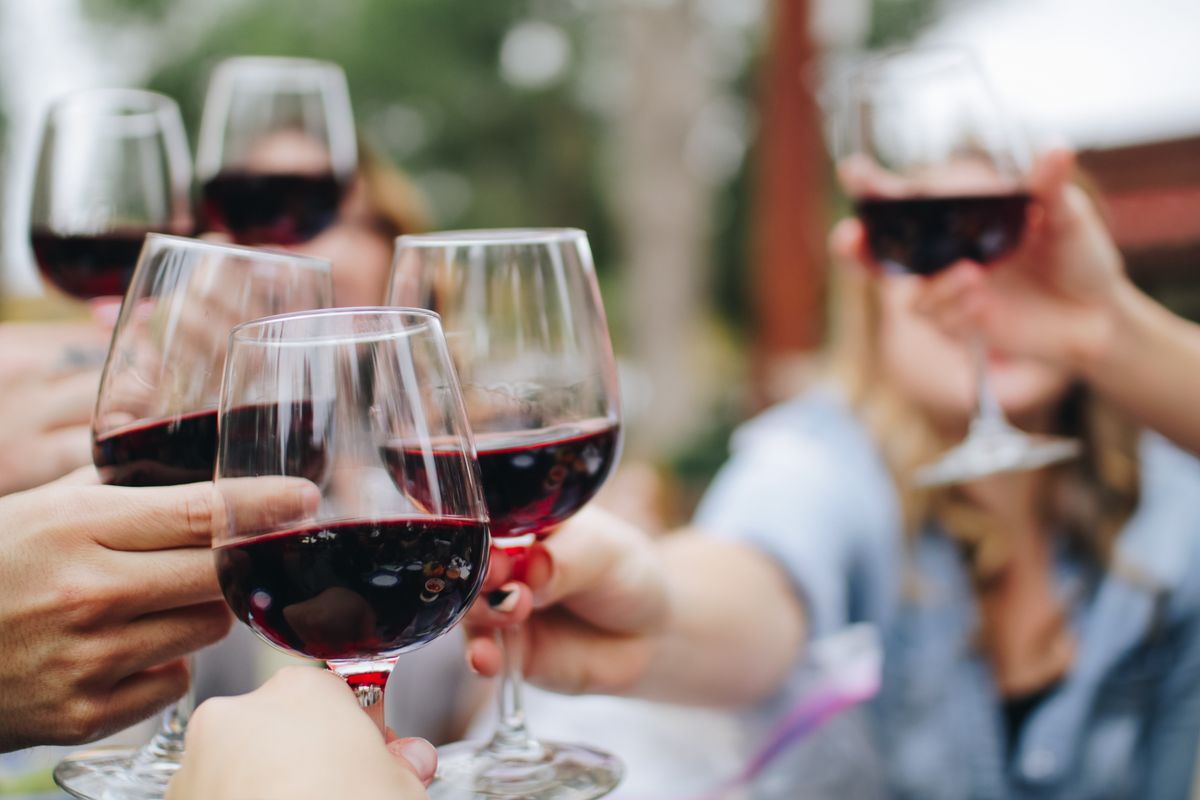 A group of people holding red wine glasses