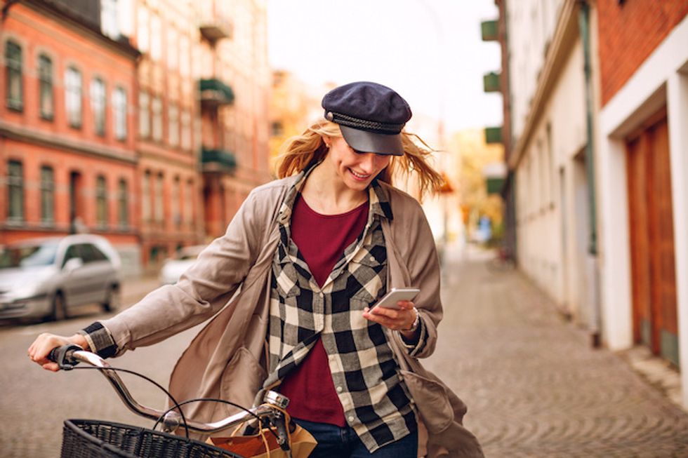 Someone on a cobbled stoned street on their smartphone, and smiling