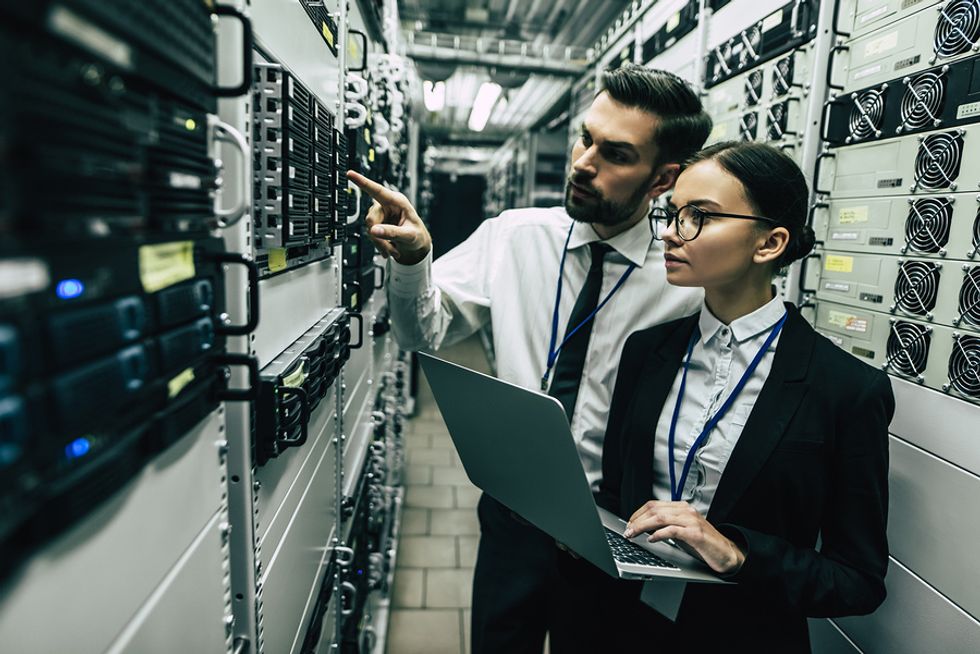 Female computer and information systems manager working with male colleague on diagnosing a computer network issue.
