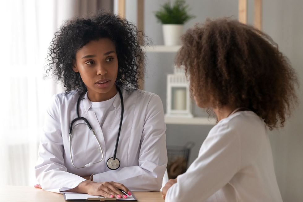 Female physician talking with a teenage patient in her office.