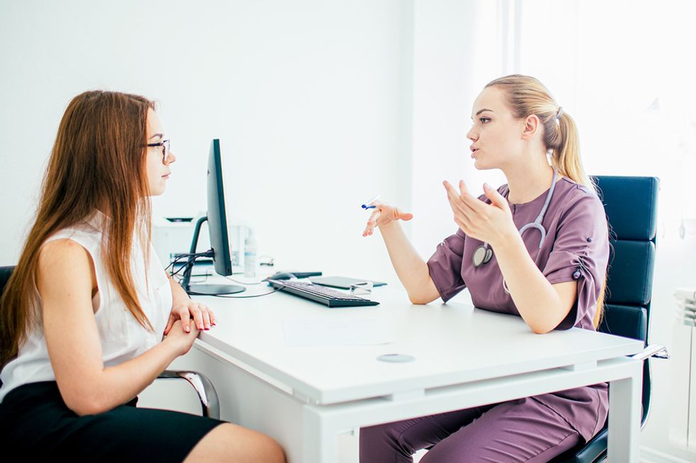 Female physician assistant consulting a female patient at her desk in a medical office.
