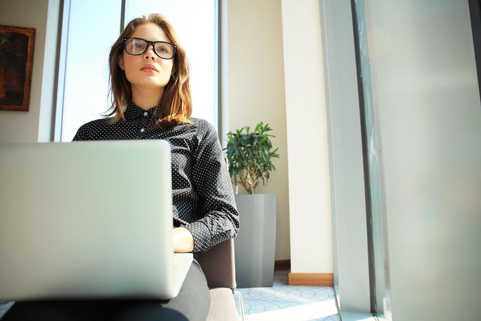 Female operations research analyst working on laptop in office and finding solutions to business issues.