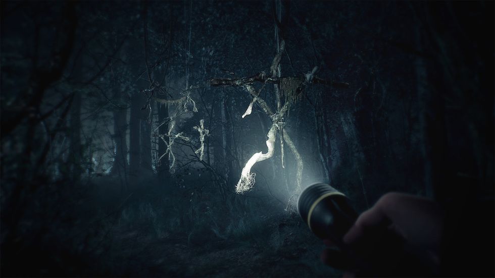 A flashlight lights up a wooden figure in the woods at night