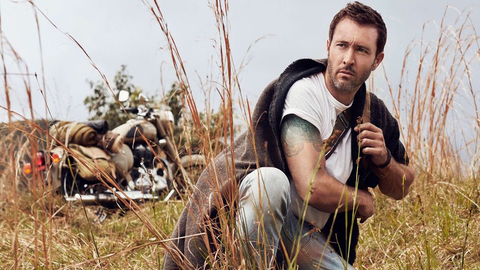 Alex OLoughlin posing in meadow