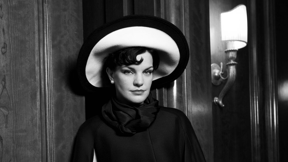Black and white image of Actress Pauley Perrete wearing a stylish hat.
