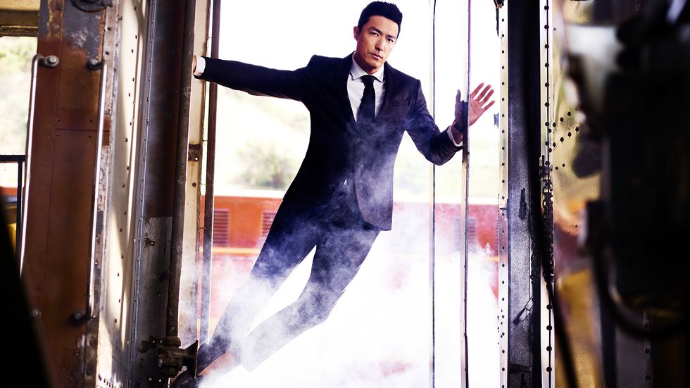 David Henney in a suit hanging onto a train