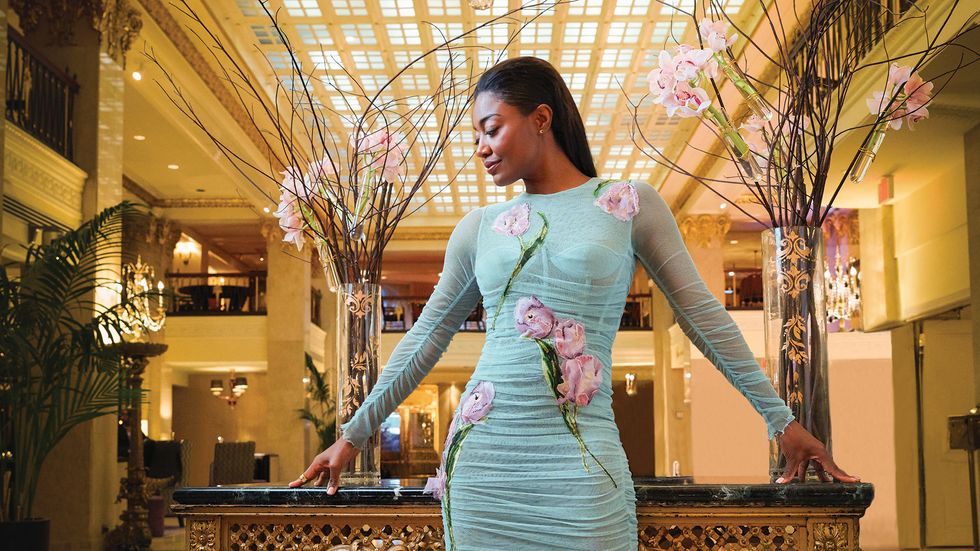 Patina Miller of Madam Secretary wearing a flower trimmed dress in front of vases