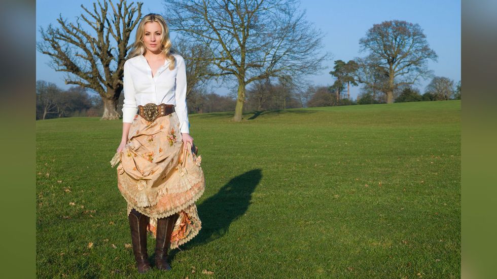 Kaley Cuoco of The Big Bang Theory in a prairie skirt and boots on a grassy knoll