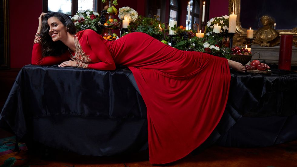 Daniela Ruah in a red dress laying on a table