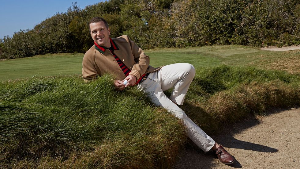 Chris O'Donnell reclines on the edge of a golf sand trap.