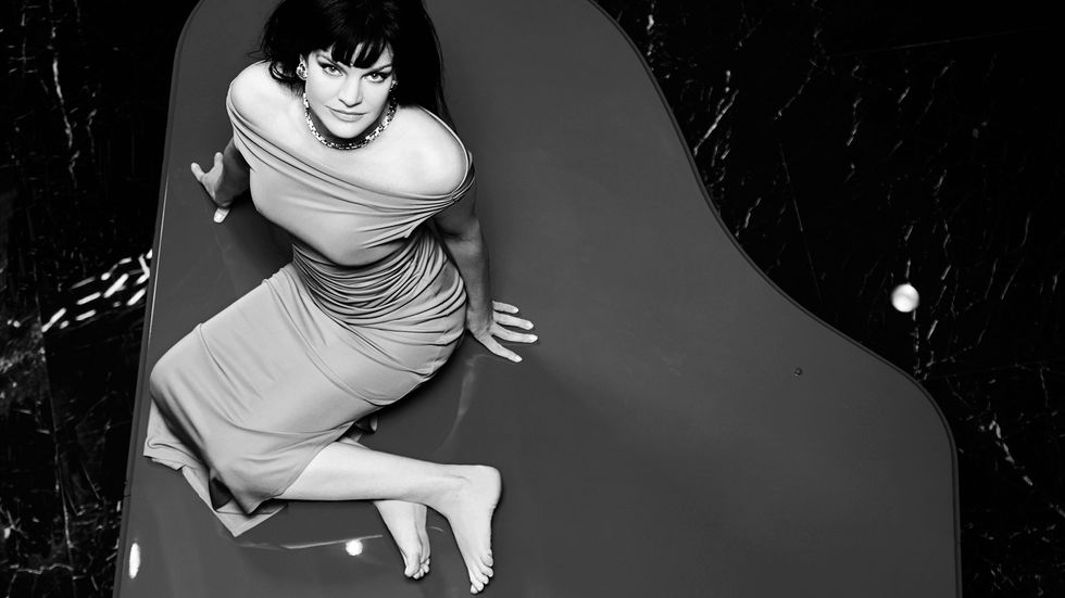 Black and white image of Actress Pauley Perrete in a sheer off the shoulder dress.