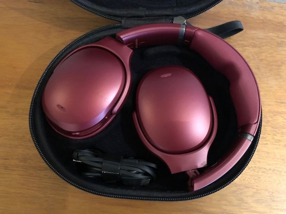 Deep red Skullcandy Crusher ANC headphones folded into their case on a wood table