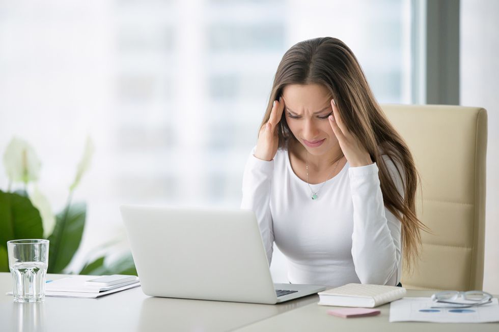 Young professional woman looking stressed at her job, debating whether she should look for a new job.