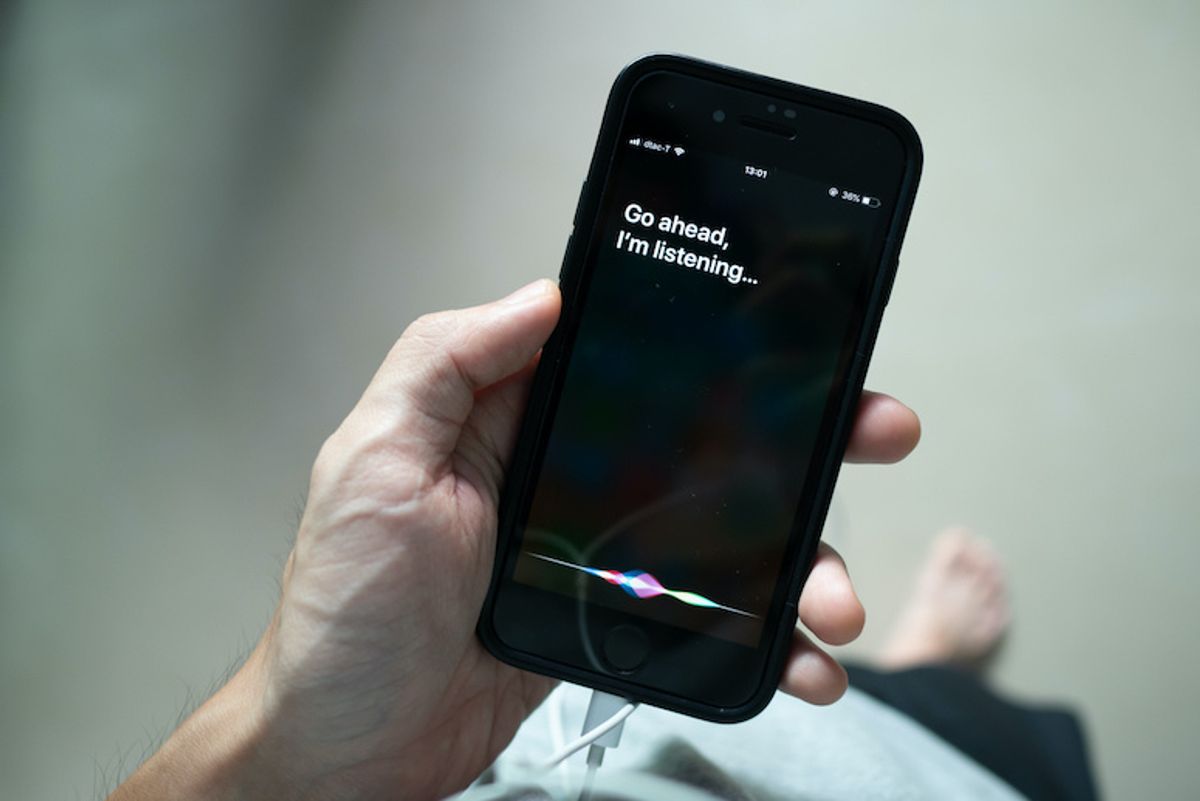 Someone holding an iPhone with a close up of Siri open and listening
