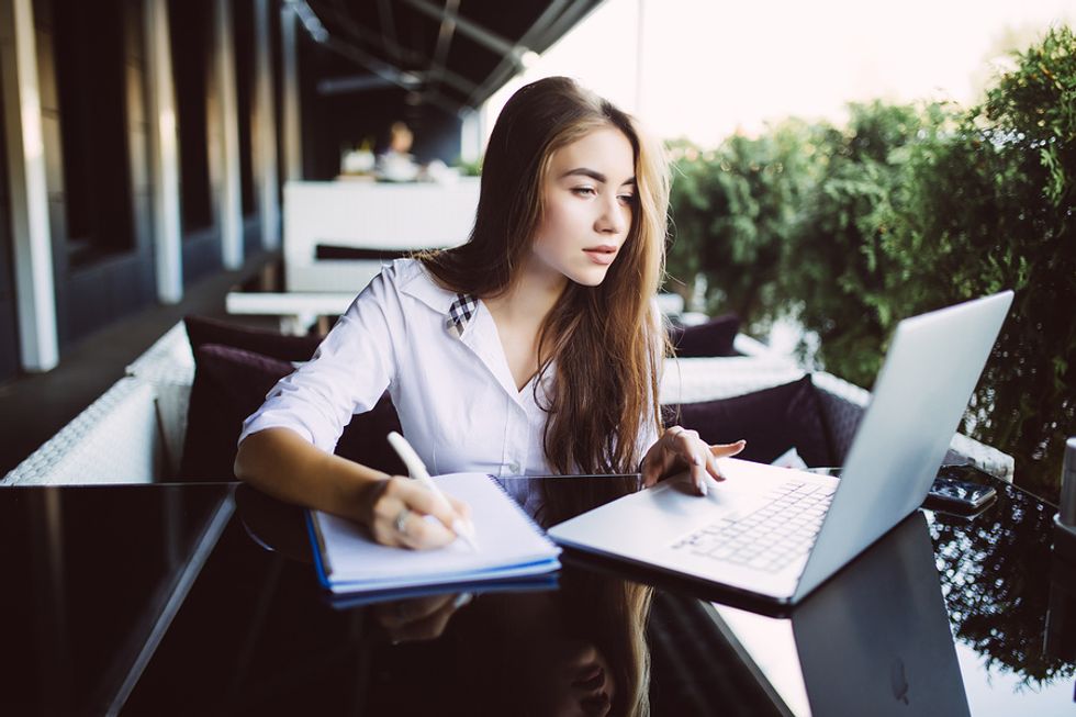 Young professional woman writing her cover letter and avoiding critical cover letter mistakes.