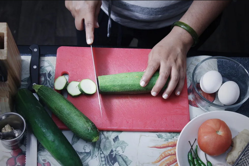 man chopping cucumber on a chopping board