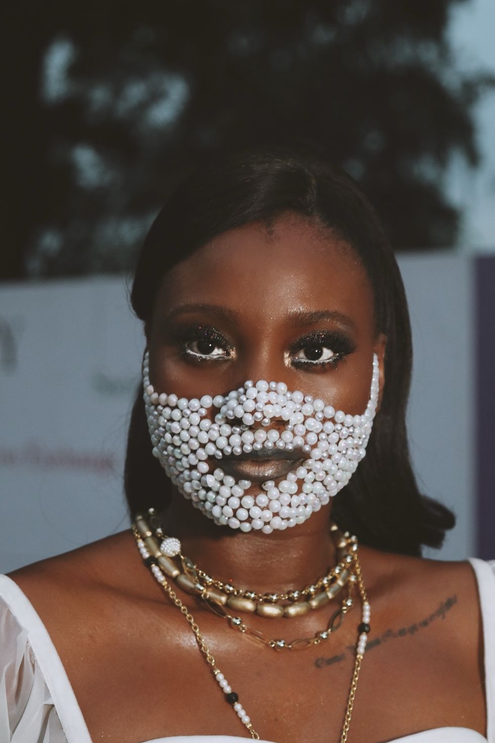 Nigerian woman wearing pearl mask and gold jewelry at Lagos Fashion Week 2019.