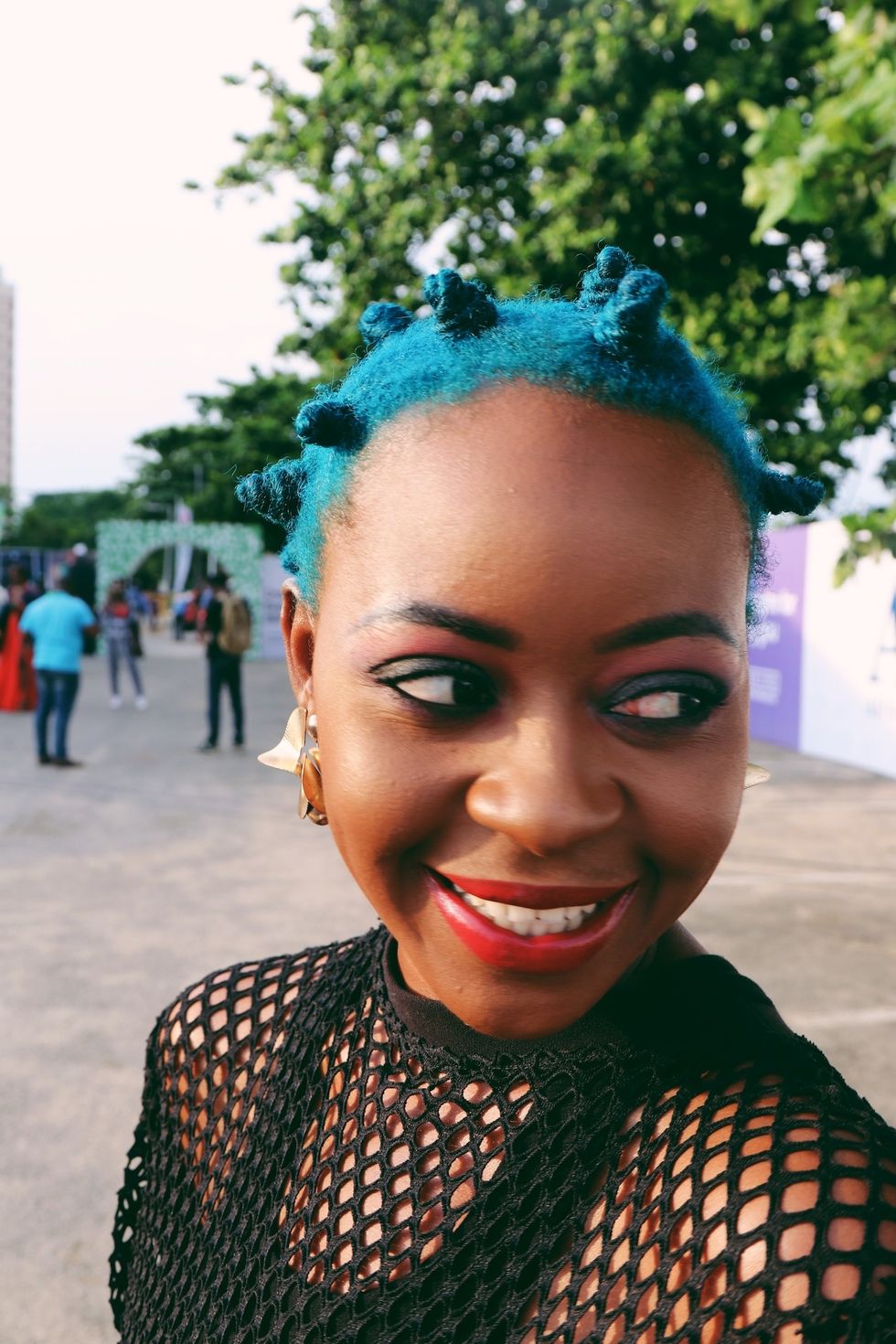 Nigerian woman with blue bantu knot hairstyle and mesh shirt at Lagos Fashion Week 2019.