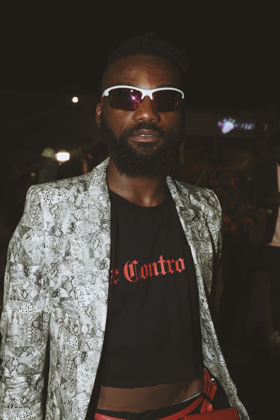 Nigerian man in snakeskin jacket, crop top and wraparound sunglasses at Lagos Fashion Week 2019.