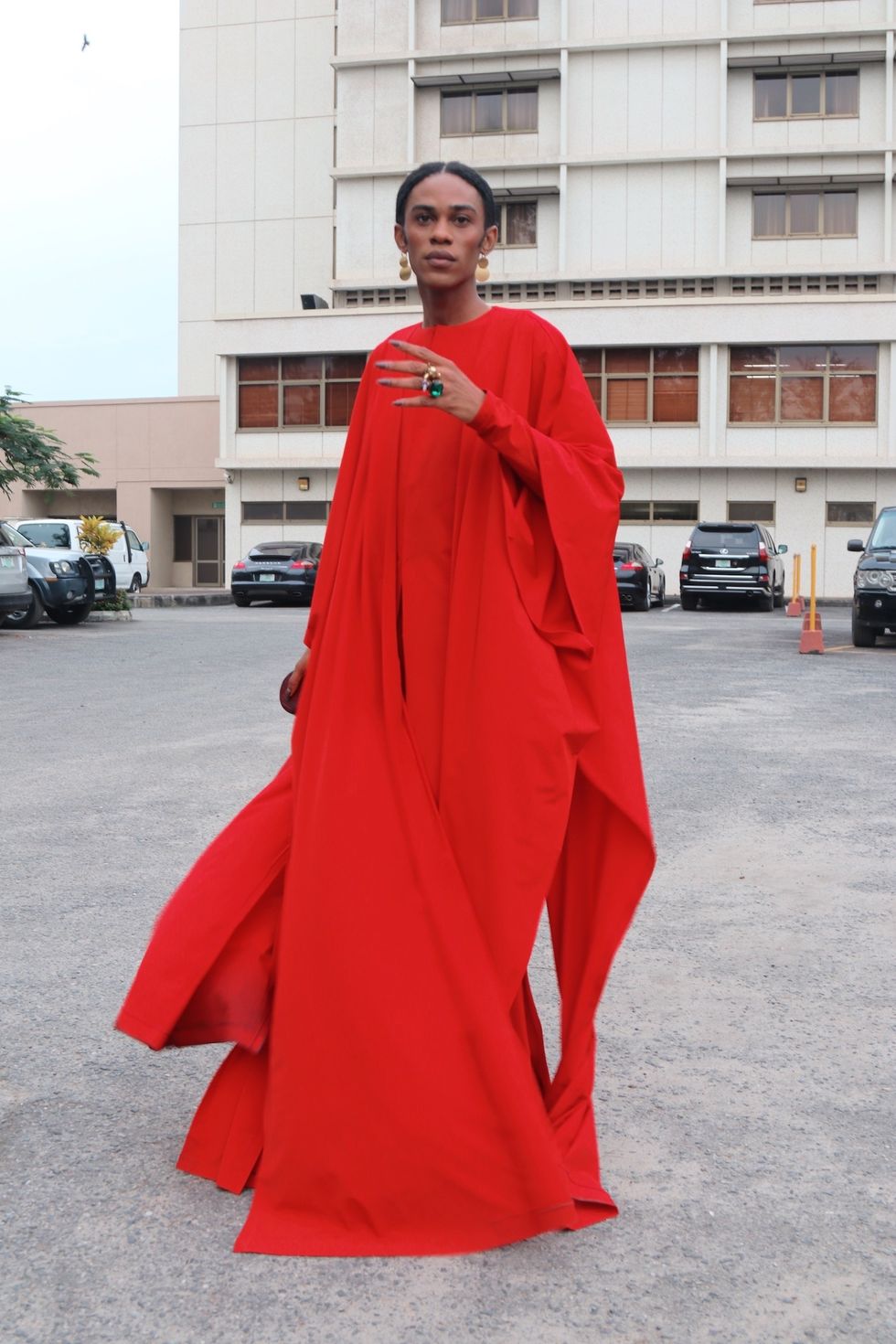 Nigerian man wearing a red dress and chunky jewelry at Nigerian fashion week.