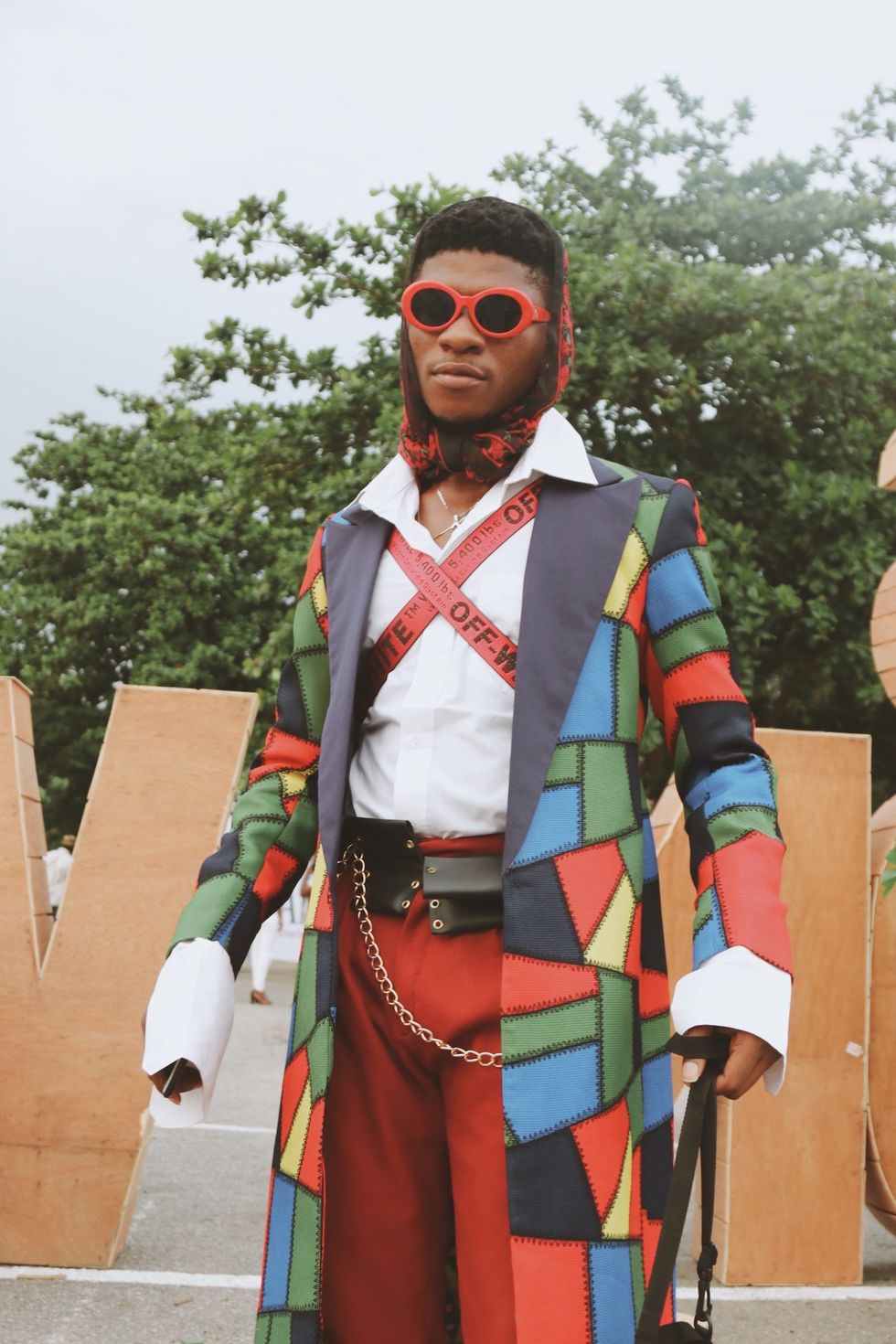 Nigerian man wearing colorful coat and red sunglasses.