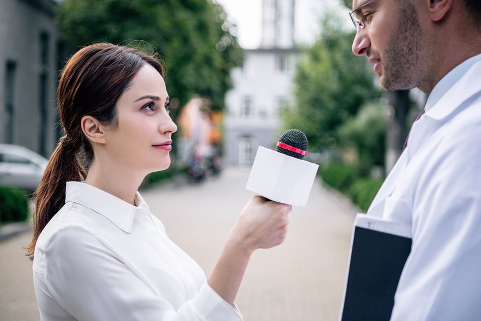 Young female journalist interviewing a doctor as she does an overseas assignment.