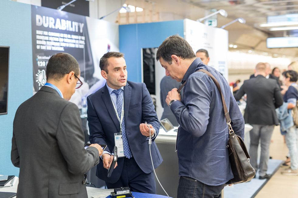 Man working at a trade show booth and giving a demonstration to potential customers.