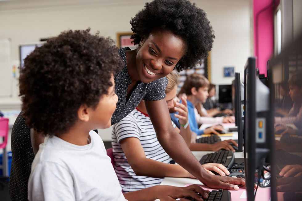 A teacher helps her student with technology in the classroom