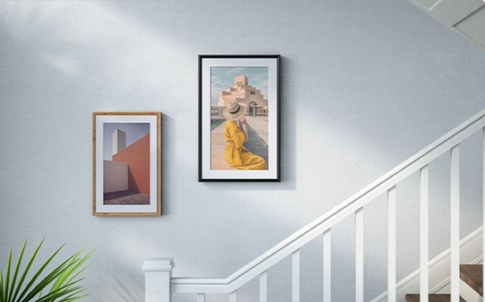 A Meural frame on a white wall with a staircase in the front of it