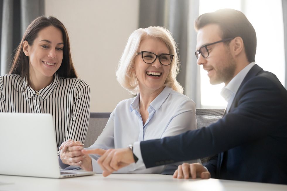 Group of co-workers smiling and talking about a team project in a meeting.