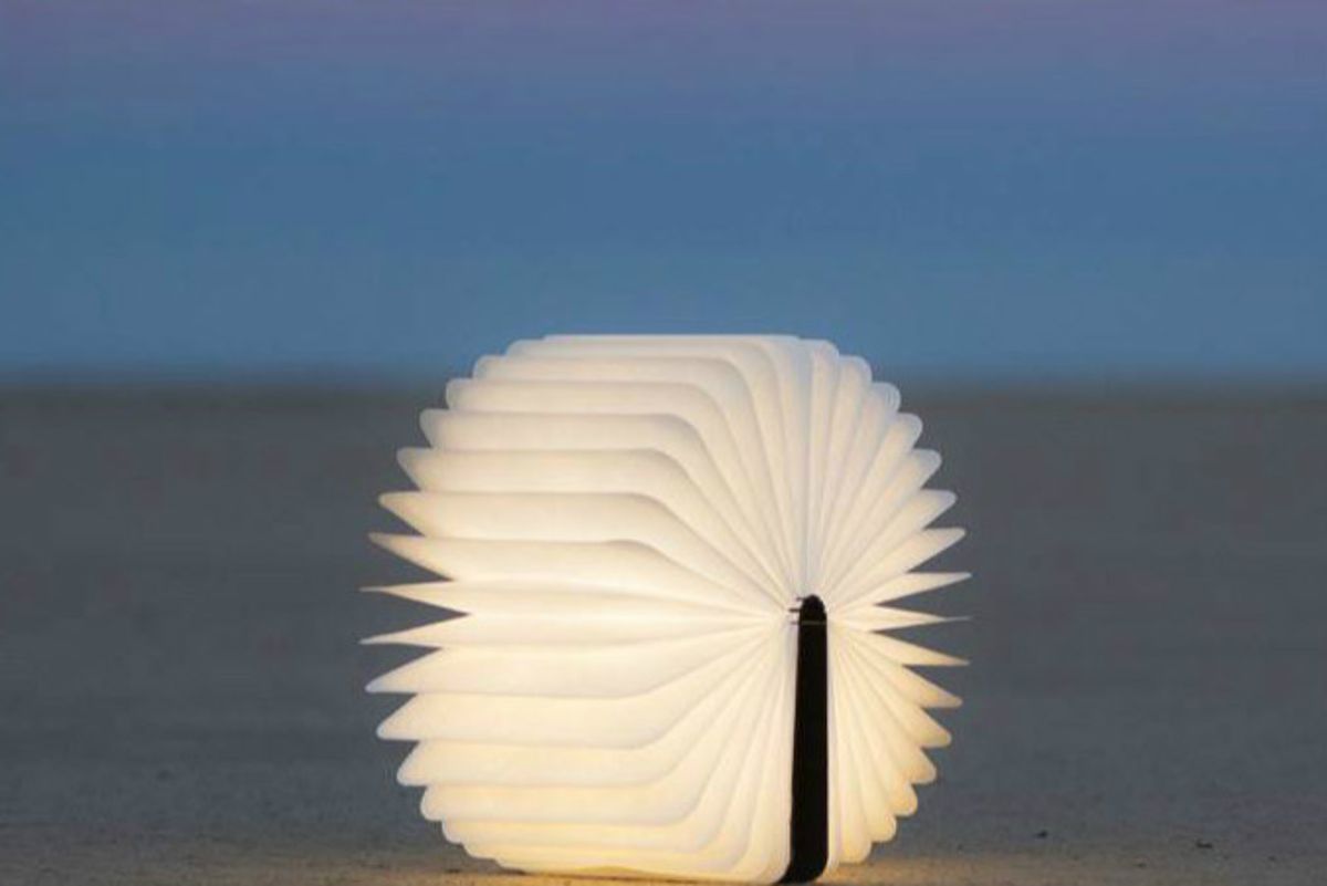 The Lumio Book Lamp opened into a pinwheel shape on a sandy beach