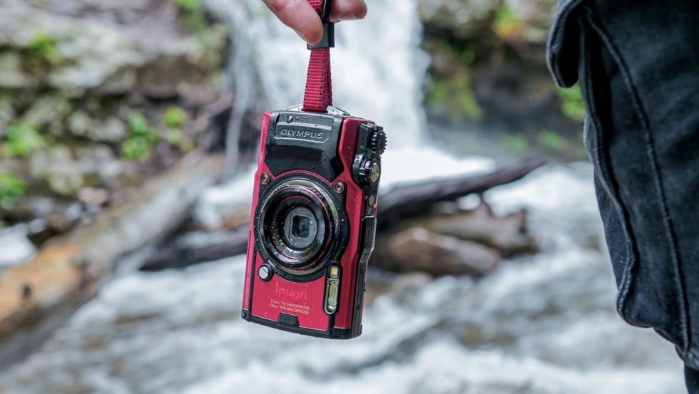 The Olympus Tough TG-6 in red being carried over a river