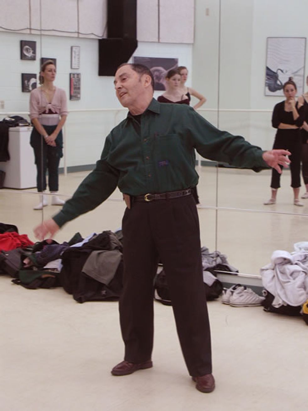 Alberto Alonso stands at the front of the studio, wearing a green button-down shirt and brown pants.