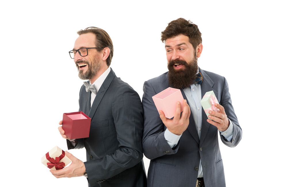 Two co-workers exchange gifts during an office holiday party.