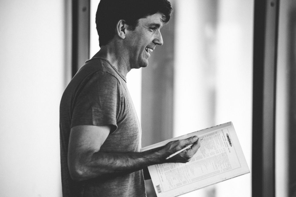In black and white in profile, Lincoln Jones, wearing a t-shirt, holds a musical score and pencil. He is smiling.