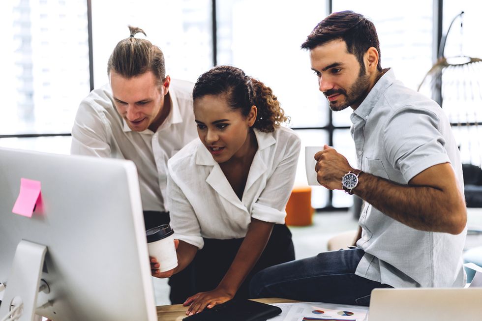 A group of co-workers work collaboratively together on a work project.