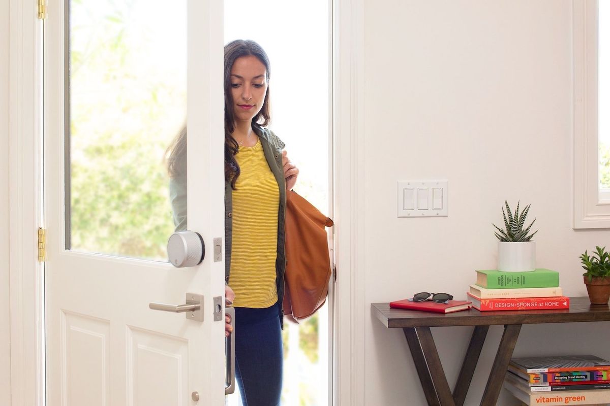 A woman walking into a home with a Yale smart lock on the door