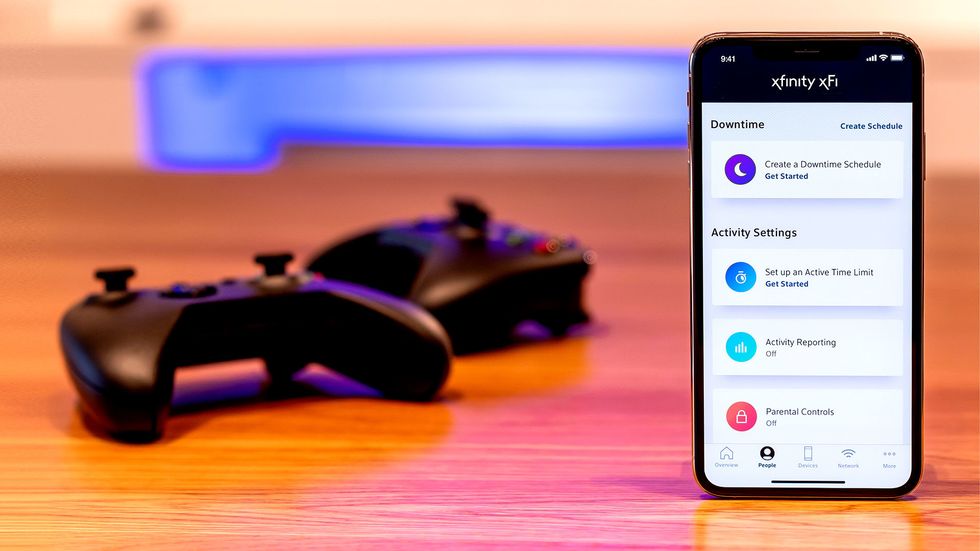 photo of smartphone with xfinity xfi app open and two xbox controllers.