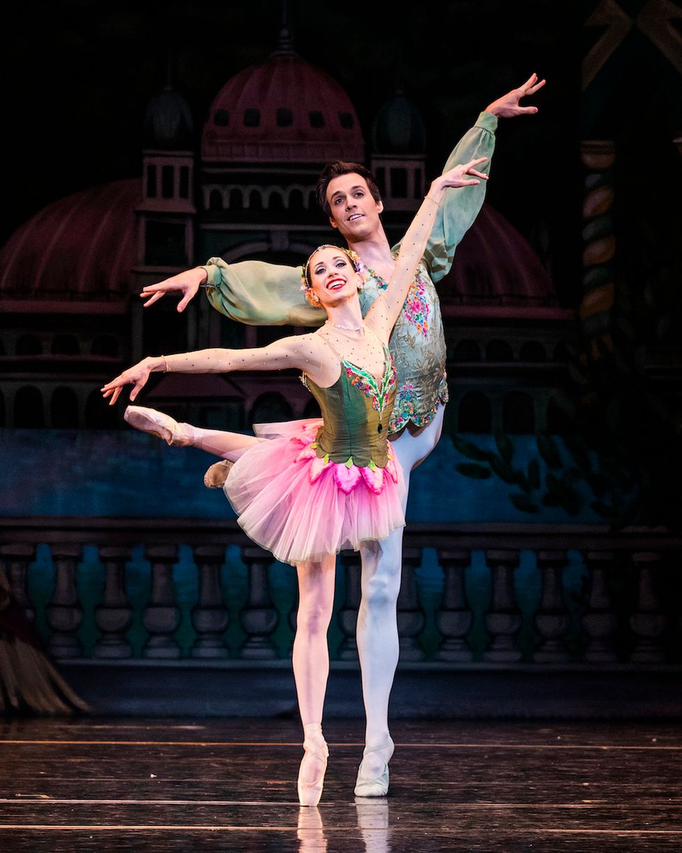 Katherine Lawrence, in a green and pink tutu, and Chase O'Connell, in white tights and a green tunic, balance on their right leg with their left leg lifted behind them in attitude.